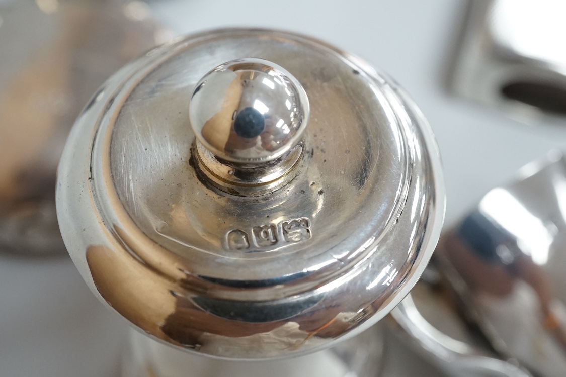 Four assorted silver condiments including a Victorian bun salt and a late Victorian pepper mill, together with a small silver bowl, a silver matchbox sleeve and a small silver two handled cup.